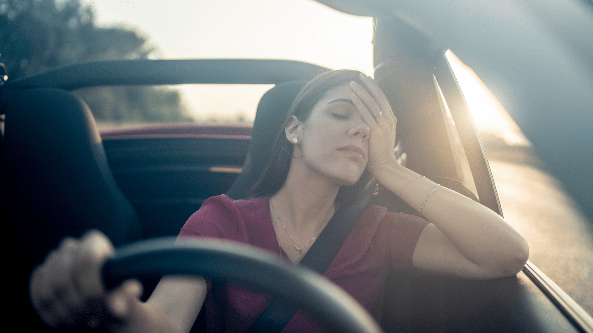 Woman closing her eyes and touching forehead while driving
