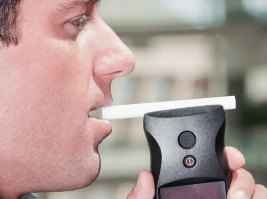 Man about to blow into black breathalyser