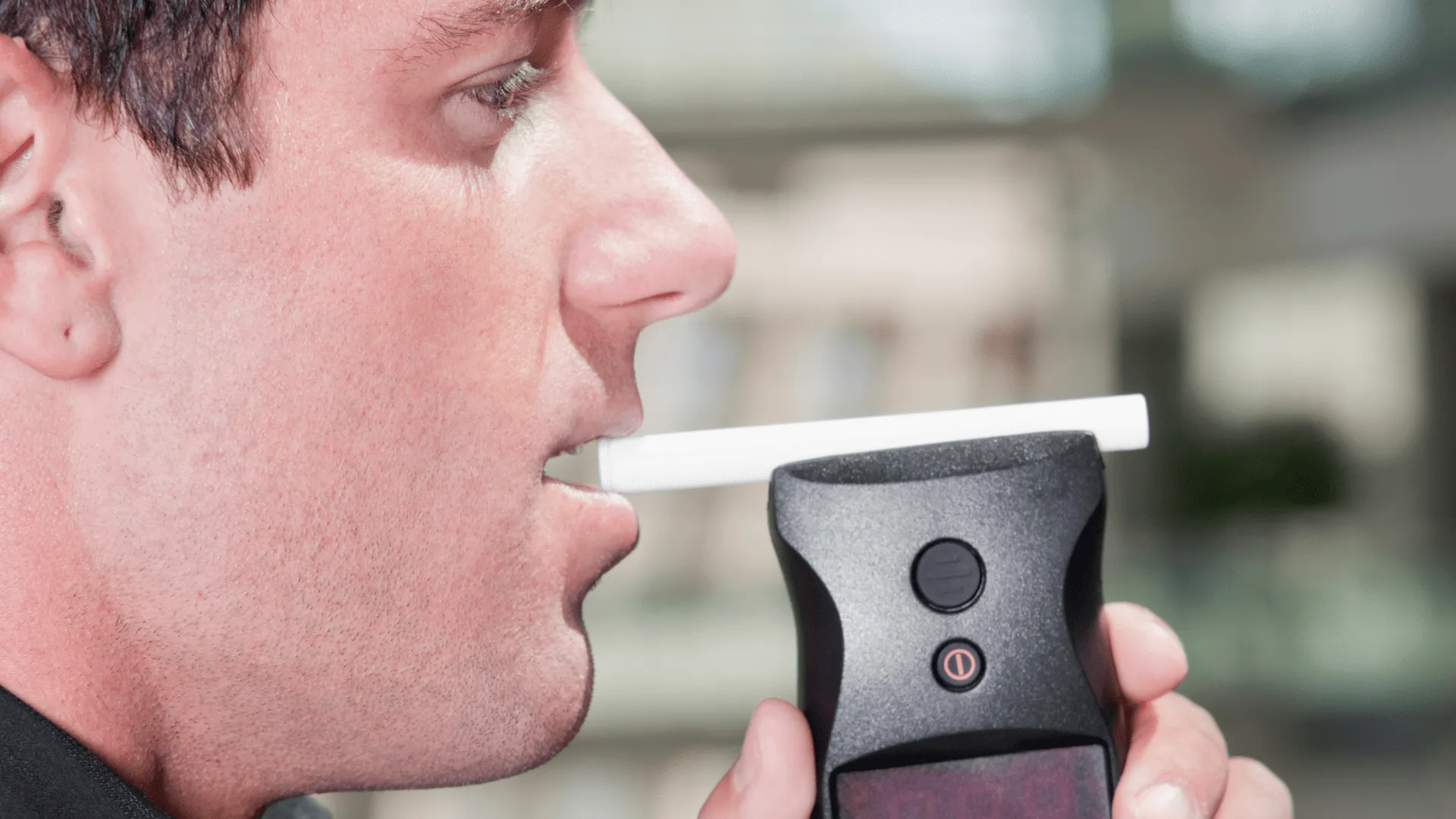 Man about to blow into black breathalyser
