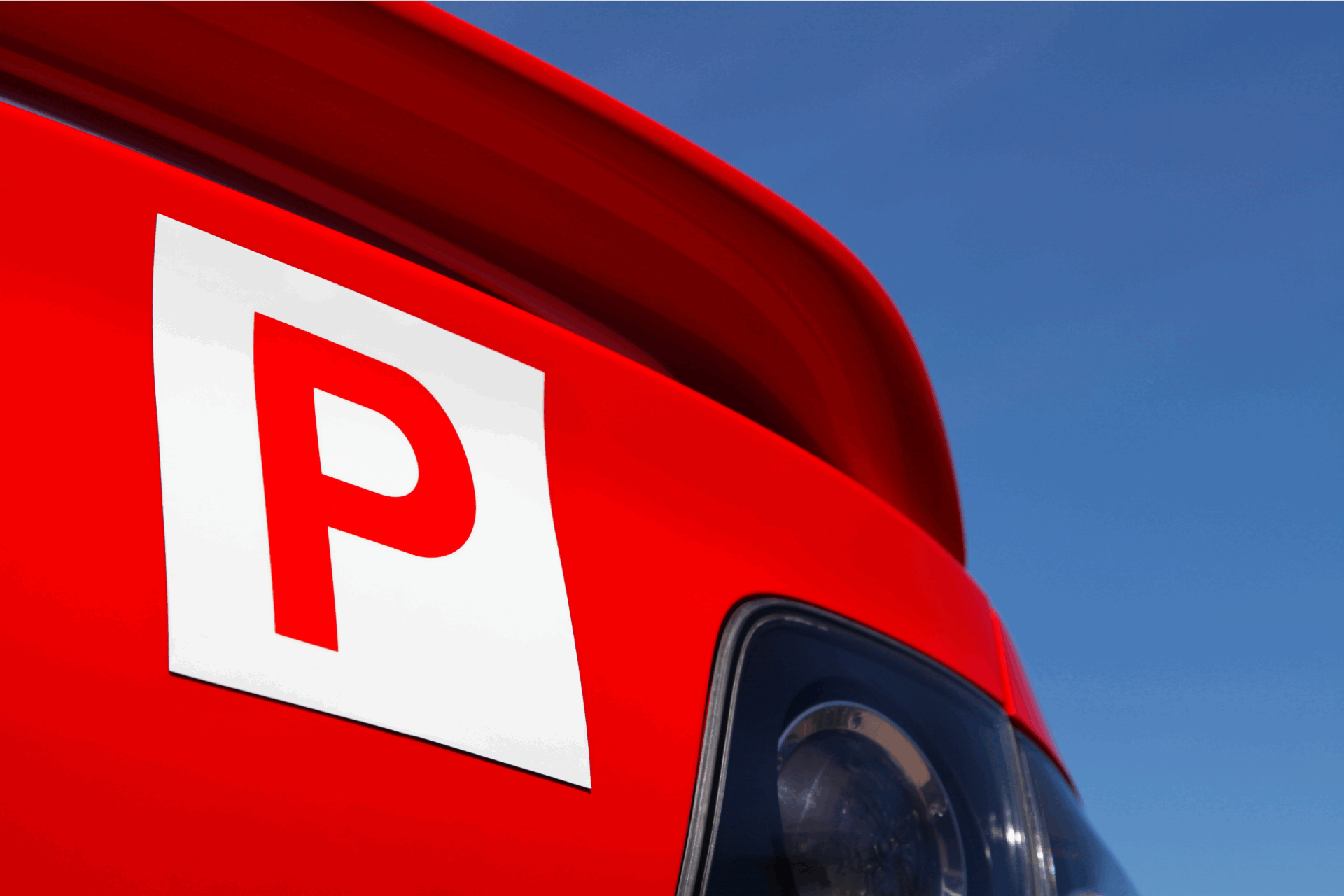 The back corner of a red car with a red P place